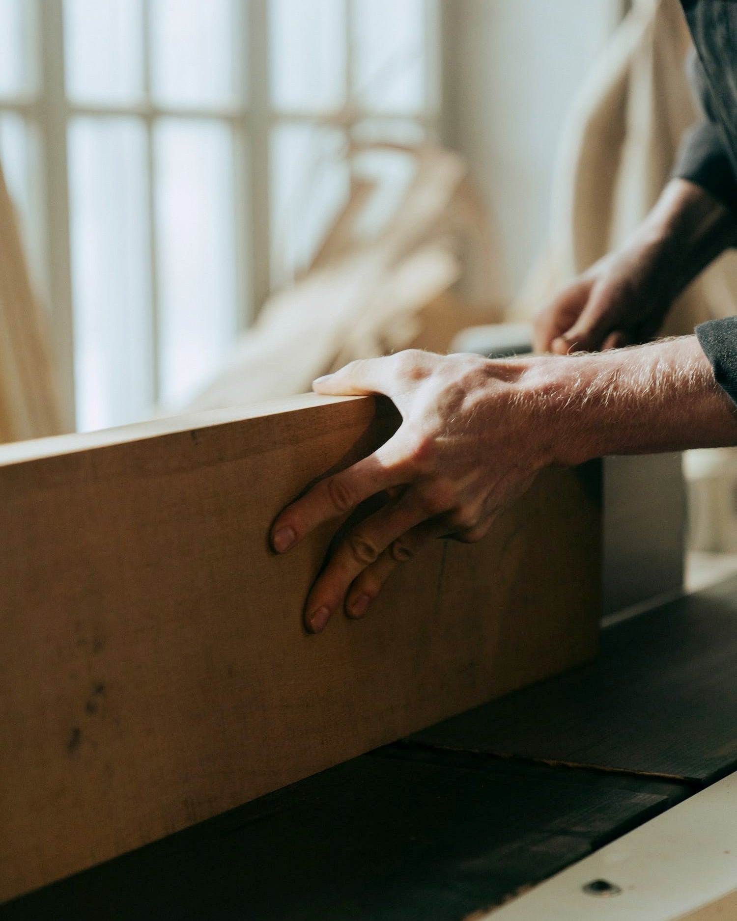 Person in einer Werkstatt bearbeitet ein Stück Holz