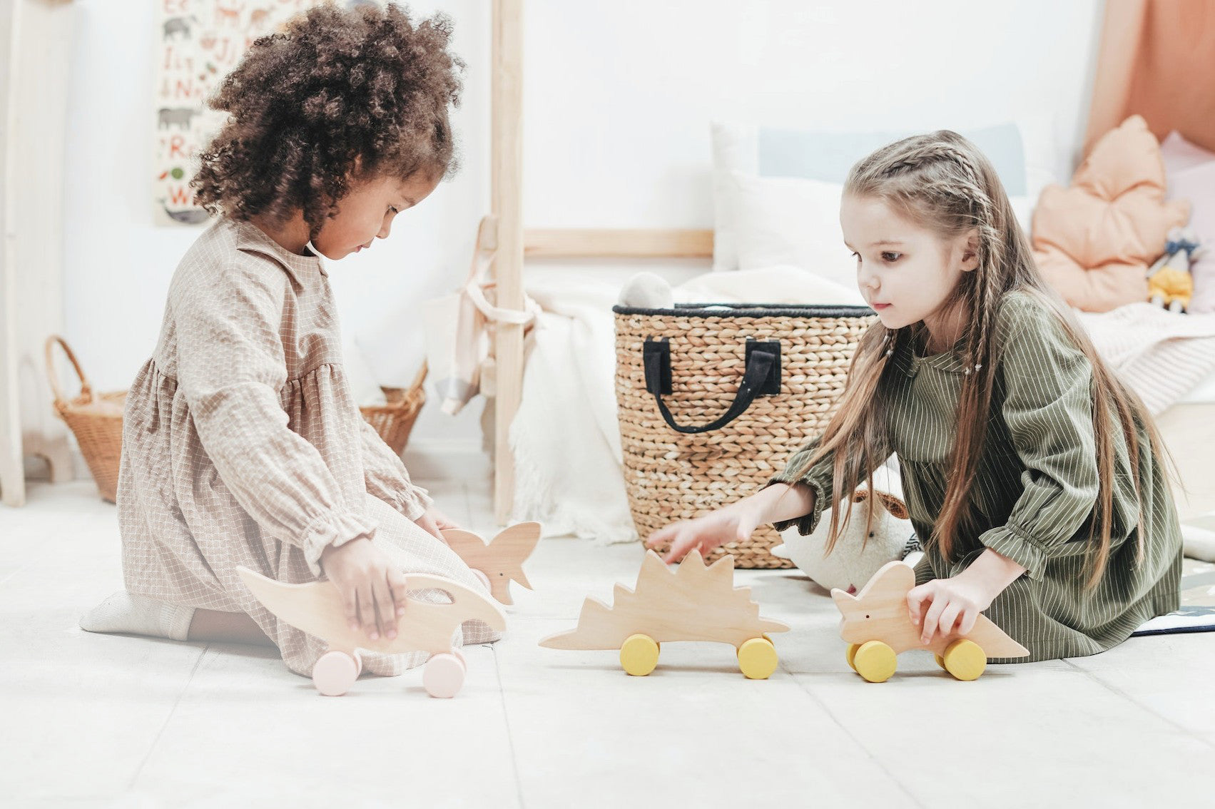 Zwei Kinder spielen in einem freundlich hellen Kinderzimmer mit Holzspielzeug.